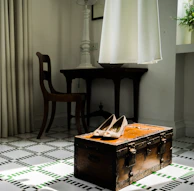 A rattan chest placed at the foot of a bed, doubling as storage and a bench.