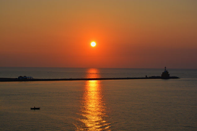 A vibrant sunset over a secluded Philippine island beach with a small fishing boat anchored near the shore.
