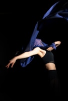 The founder executing the iconic spin mid-motion, with flowing royal blue fabric creating a dynamic visual.