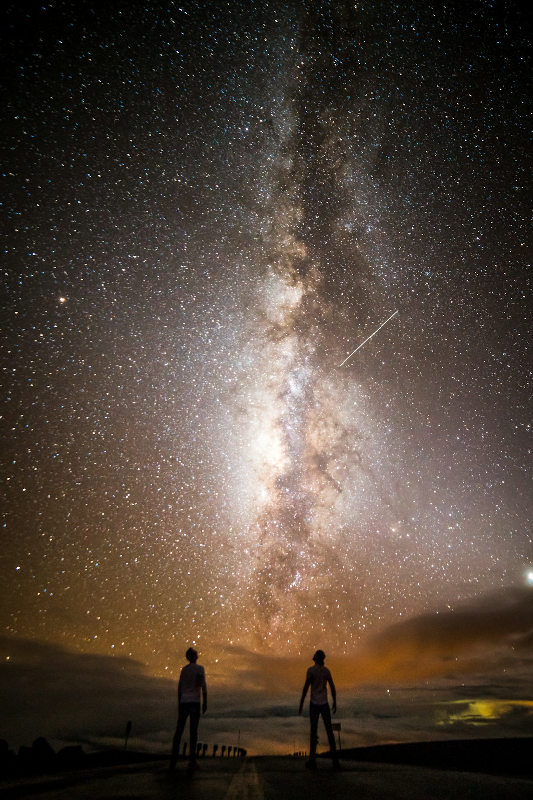 two people standing under milky way at night