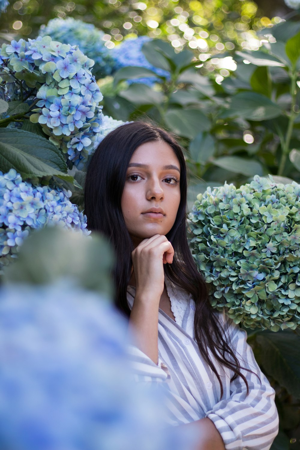 woman with chin on hand surrounded by plants