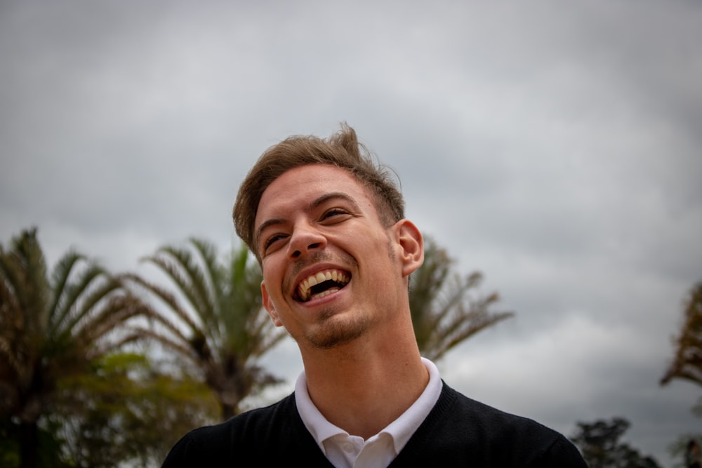 laughing man wearing black shirt and white collared shirt