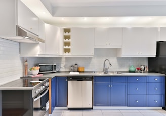 a kitchen with blue cabinets and a black refrigerator