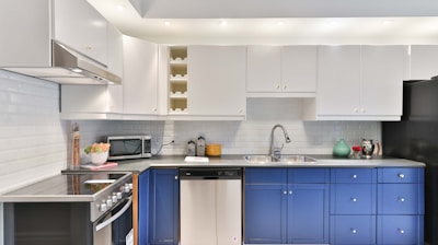 a kitchen with blue cabinets and a black refrigerator