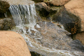 Waterfall mini aquarium with cascading water over smooth stones, softly illuminated.