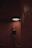 A dancer in a dark leotard gracefully stretches upward, reaching toward a bright circular light on the ceiling. The setting features warm, textured walls with a word 'Southbound' visible on one side.