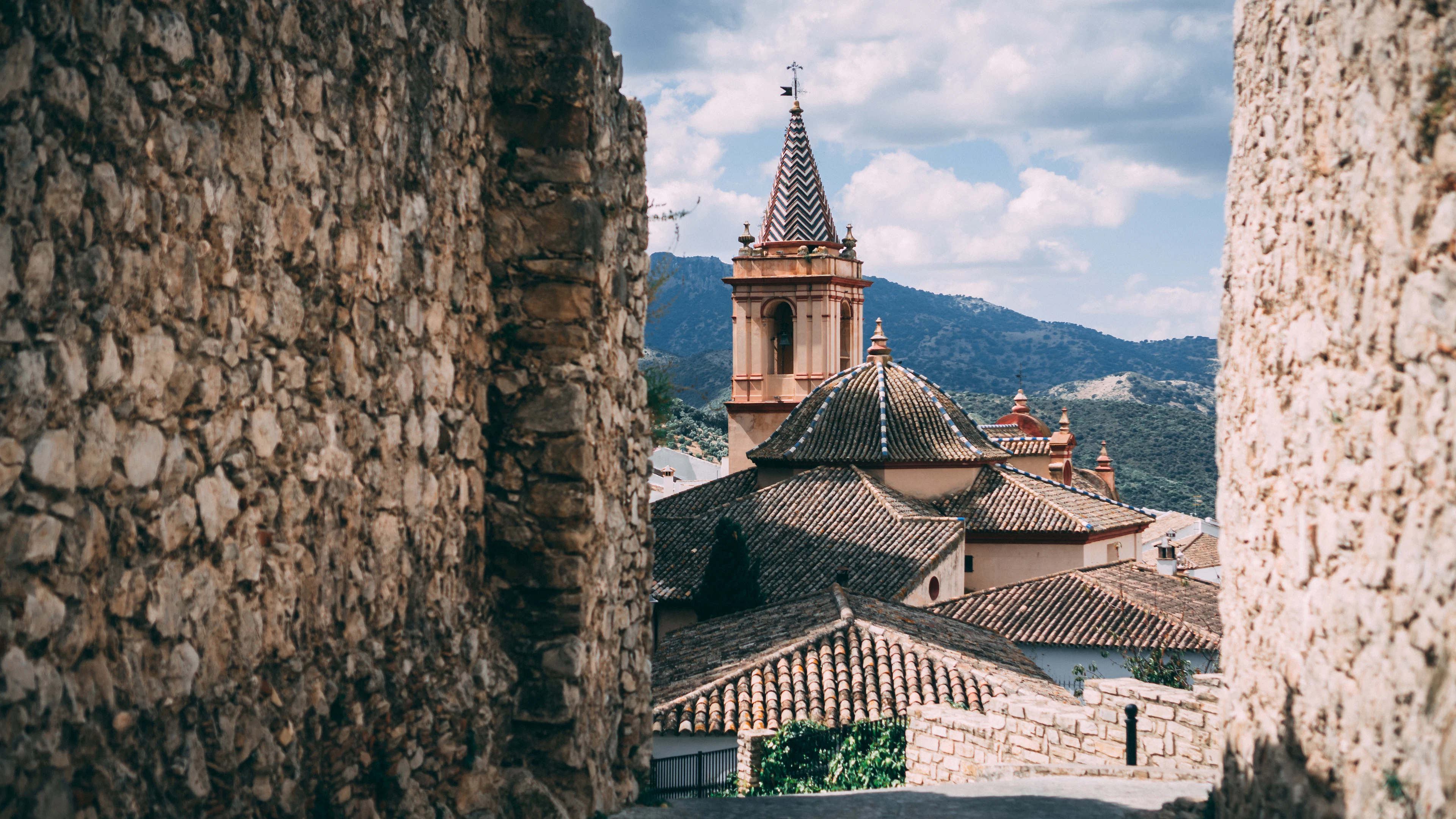 The old church tower and tiled roofs framed by stone walls in Zahara de la Sierra