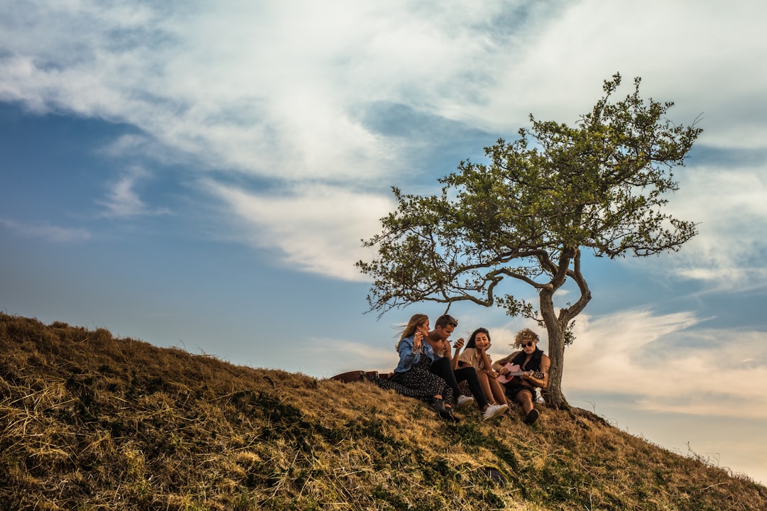 3 women sitting on brown grass field during daytime