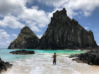 A local guide pointing out a hidden fishing spot beyond the reef with a backdrop of endless blue sea.