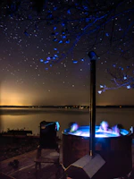 Evening shot of a minimalist sauna illuminated against a backdrop of dark trees and starry sky.