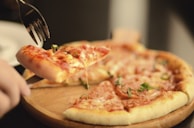 A freshly baked pizza being sliced, steam rising from the hot crust.