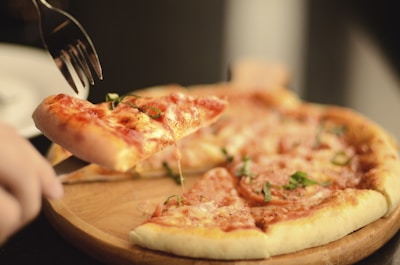 Close-up of a delicious, freshly baked pizza being sliced on a wooden board.