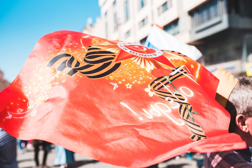 a man holding a large red flag in the street