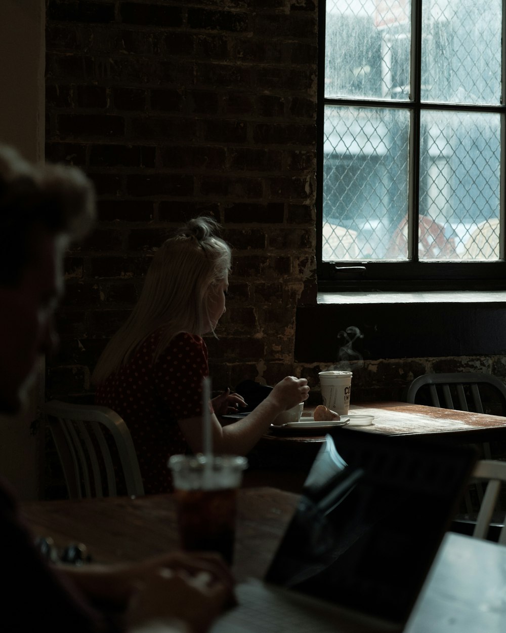 woman sitting on table beside window