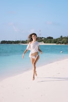 A joyful traveler standing on a pristine white sand beach with turquoise waters.