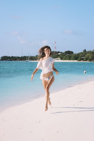 A vibrant photo of a model wearing a turquoise fitness outfit running along the beach at sunrise.