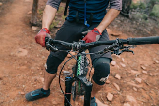 Wrist guards worn by a cyclist gripping handlebars on a mountain trail