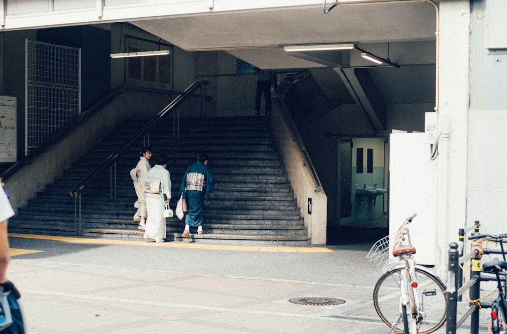 three Geisha standing beside stairs