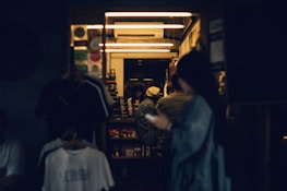 A warm interior scene blending clothing racks with people enjoying casual drinks.