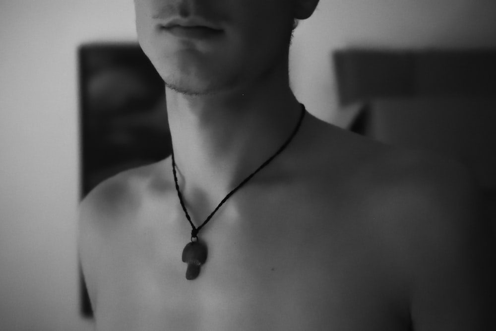 topless man wearing black necklace