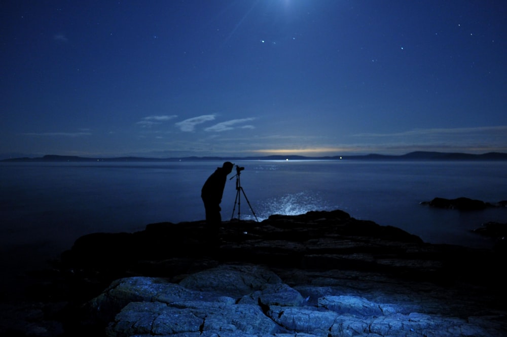 man taking photo with camera on tripod in beach