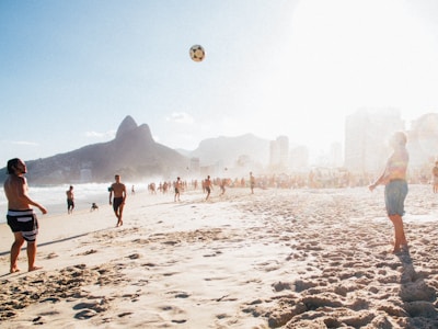 A vibrant beach scene with athletes playing futevôlei.