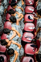 A group of young individuals wearing camouflage uniforms are huddled together in a friendly, supportive manner. They are in a large room with red chairs arranged in rows. Some of the chairs have pamphlets and water bottles placed on them.