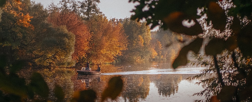 two people in a boat on a lake surrounded by trees