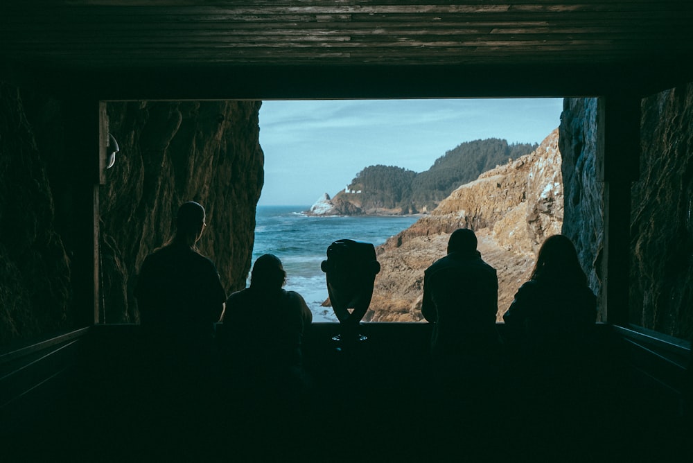 silhouette of four people facing cliff near sea