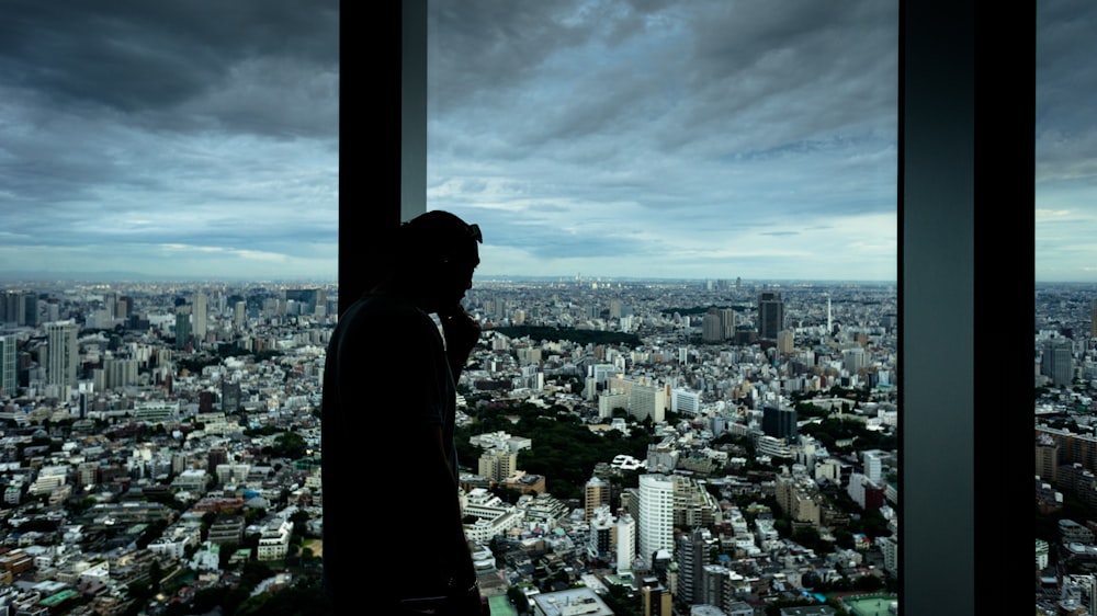 silhouette of man standing beside glass window