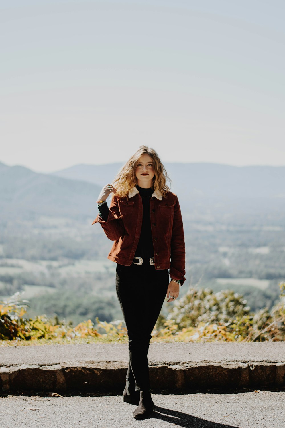 woman standing on road holding her hair