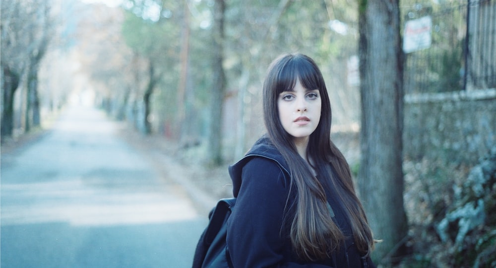 woman standing wearing black jacket at road