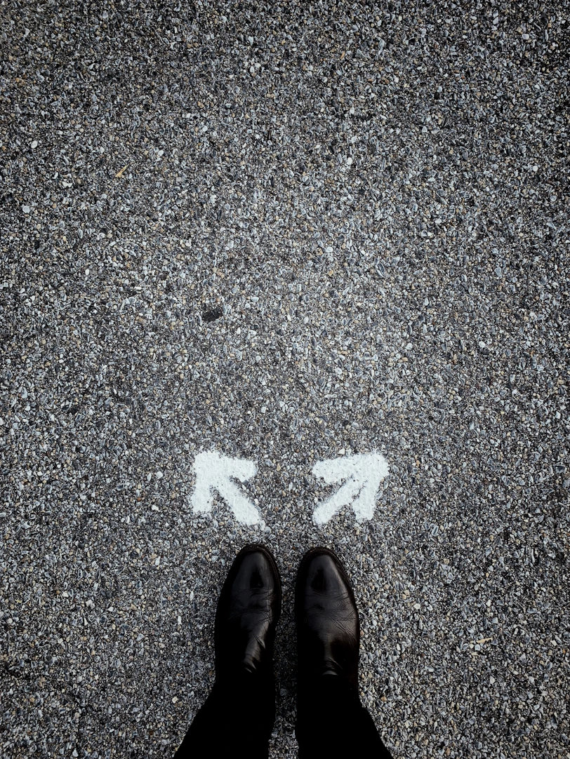 feet on asphalt between two directional arrows