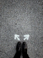 feet on asphalt between two directional arrows