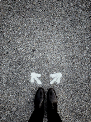feet on asphalt between two directional arrows
