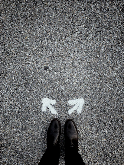 feet on asphalt between two directional arrows