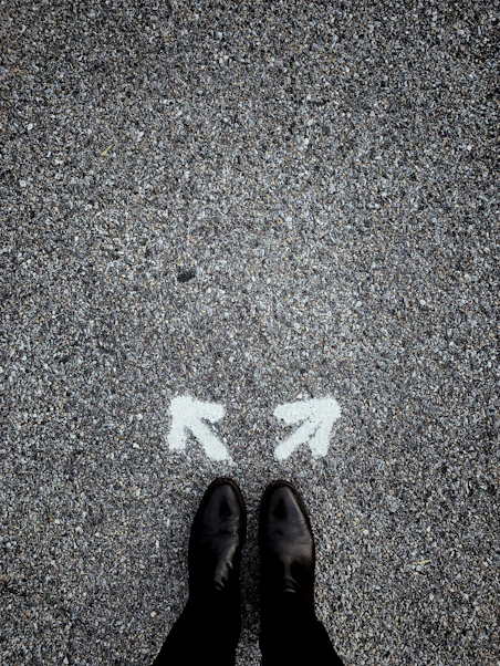 feet on asphalt between two directional arrows