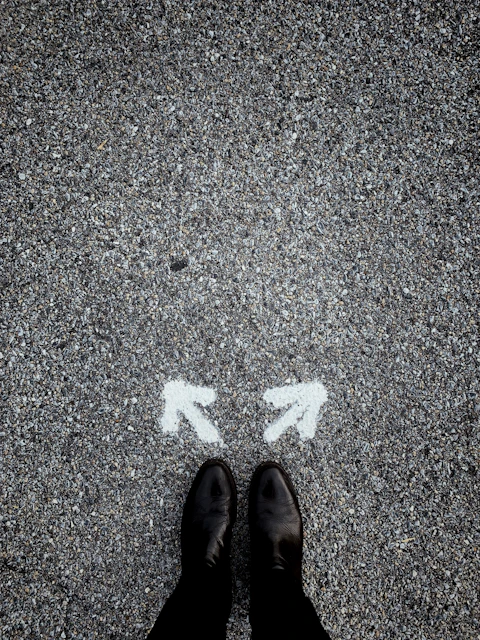feet on asphalt between two directional arrows