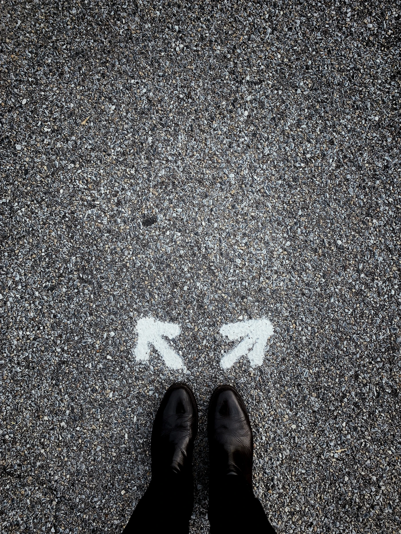 A person standing between two directional arrows painted on pavement