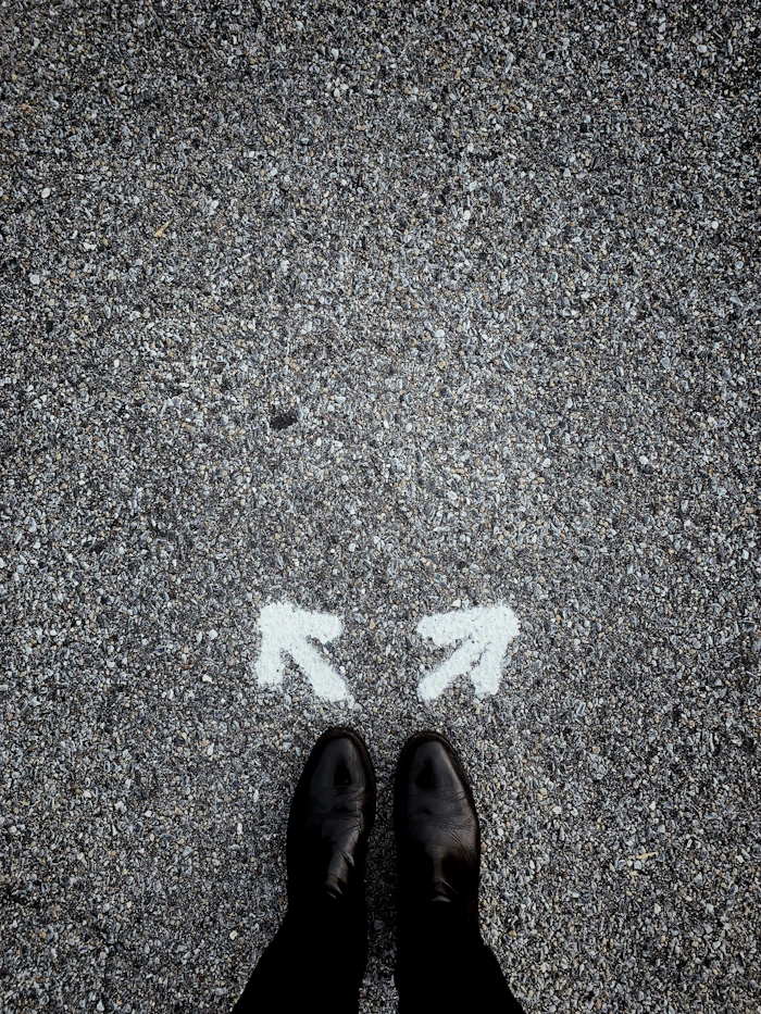 A person standing between two directional arrows painted on pavement