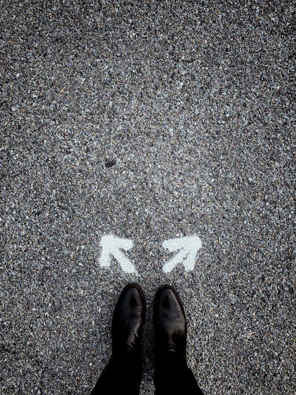 feet on asphalt between two directional arrows