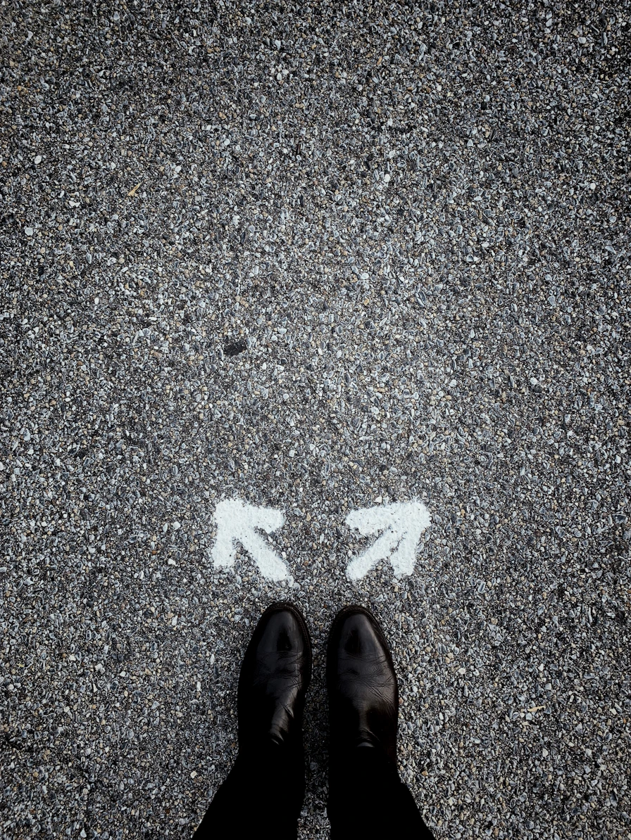 feet on asphalt between two directional arrows