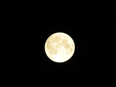 A bright full moon set against a dark night sky, showing detailed craters and surface patterns.