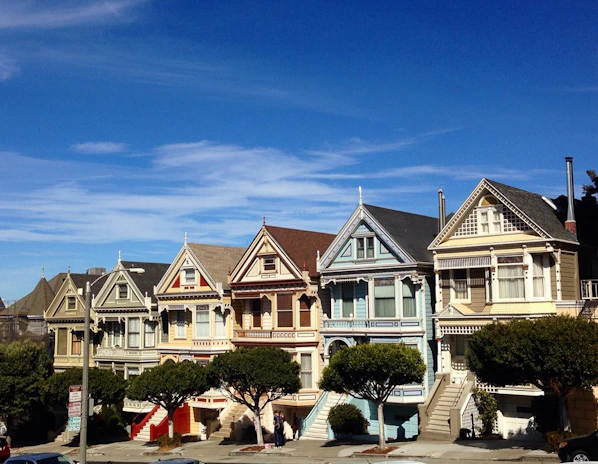 A scenic Melbourne neighborhood street with charming houses and green trees under a clear blue sky.