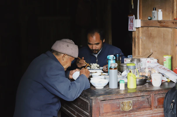 An elderly couple enjoying a warm meal together at a rustic wooden table.