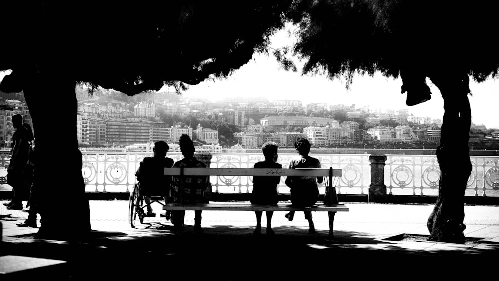 four people sitting on bench