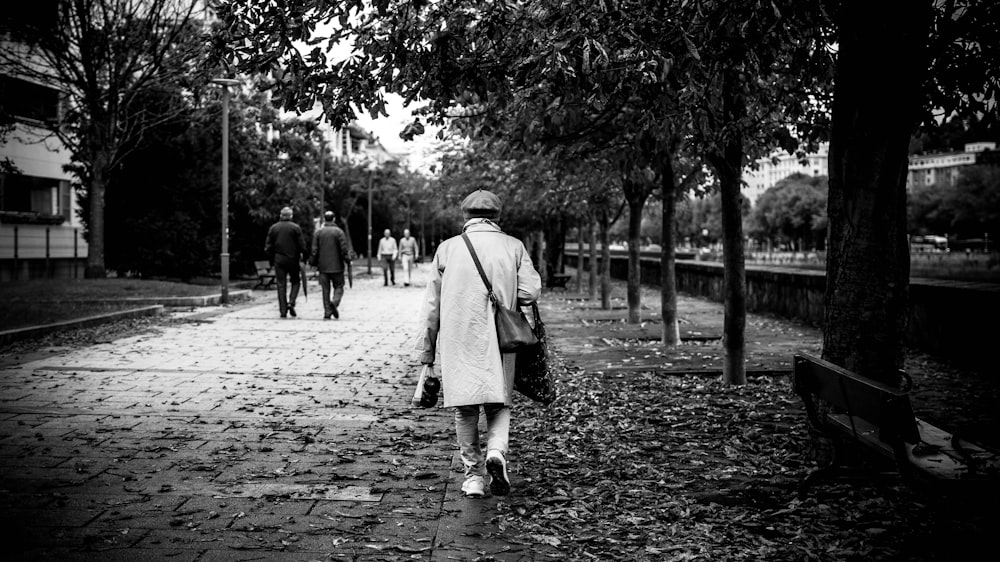 grayscale photo of person walking on concrete ground