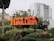 A neon sign with the text '11 we are MILLION' stands amidst lush greenery, with modern urban buildings in the background.