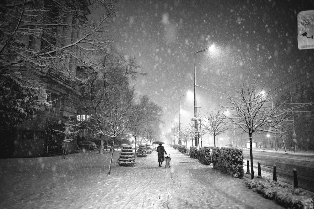 Person, die in einer verschneiten Nacht mit Regenschirm auf der Straße spazieren geht