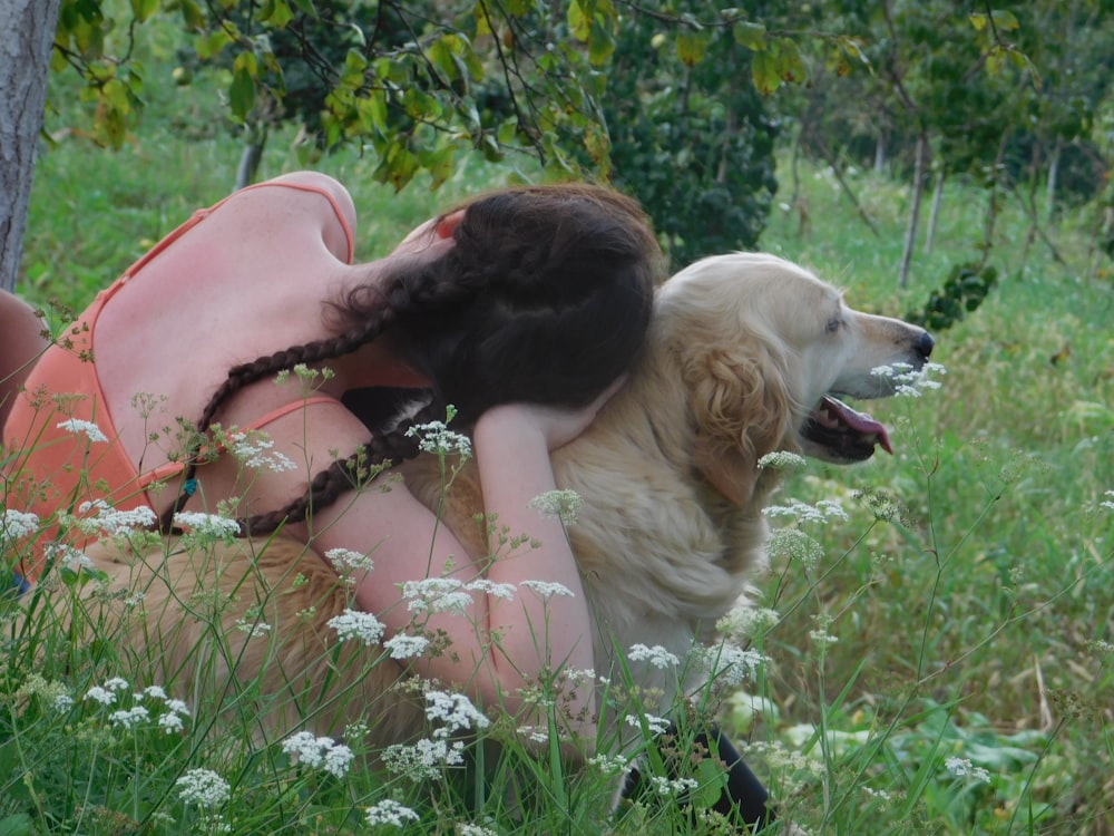 adult beige short-coated dog standing on green grass beside woman